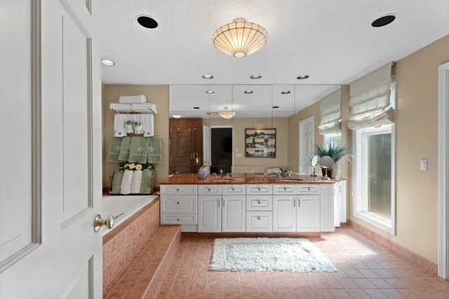 a spacious bathroom with a double vanity sink a mirror and a bathtub