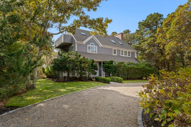a front view of a house with a yard and a tree