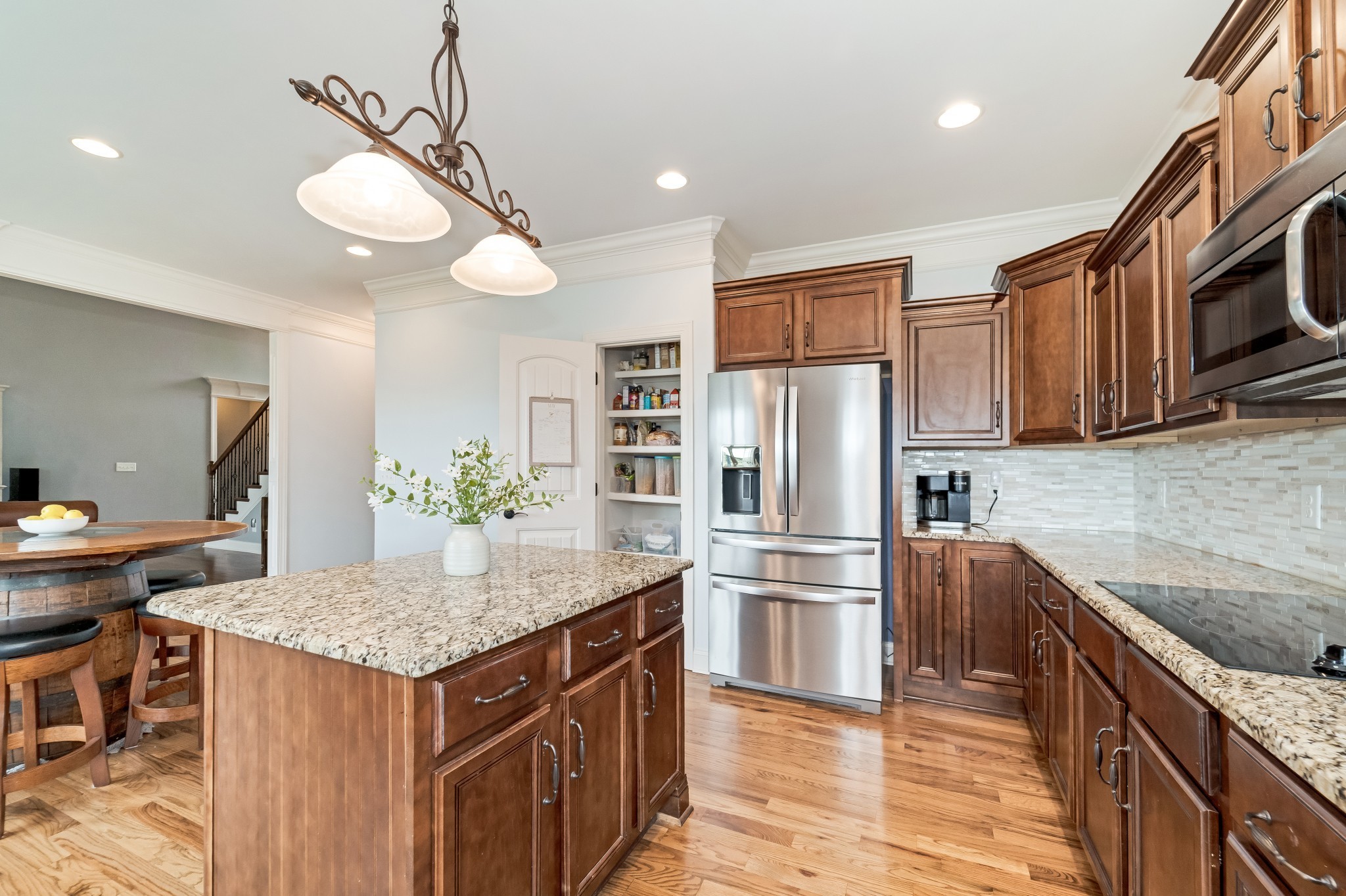 3008 Sakari Circle Spring Hill, TN 37174 - Photo 14 of 44 a kitchen with stainless steel appliances granite countertop a kitchen island a stove a refrigerator a sink a dining table and chairs with wooden floor