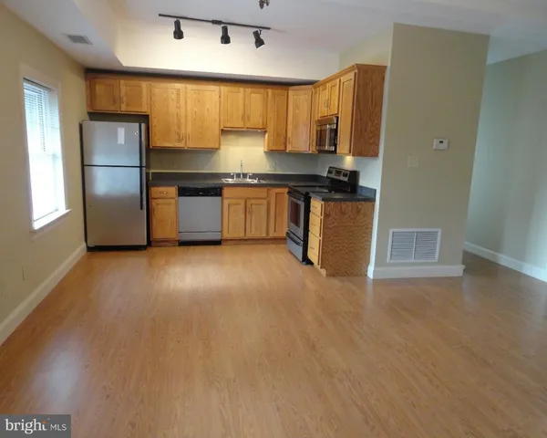 a kitchen with granite countertop a refrigerator and wooden cabinets