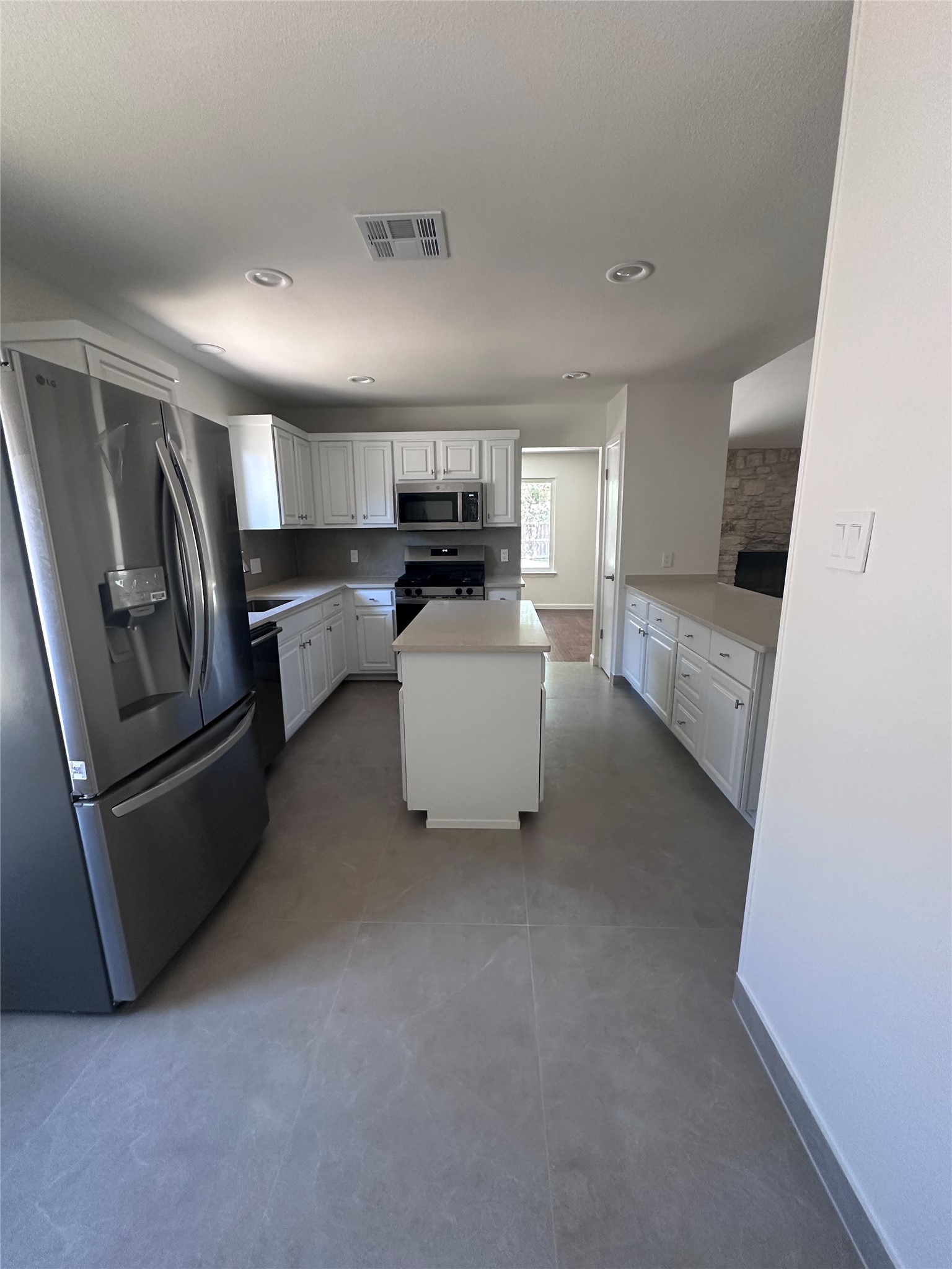 12610 Andromeda Cove Austin, TX 78727 - Photo 7 of 29 White cabinetry, solid surface quartz countertops, and modern appliances anchor this updated kitchen space.