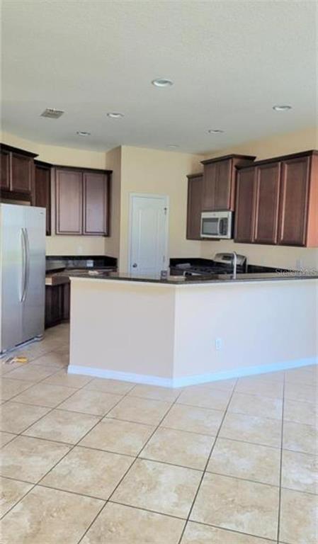 4025 Scarlet Branch Road Orlando, FL 32824 - Photo 6 of 13 a kitchen with stainless steel appliances a stove a sink a microwave and a refrigerator