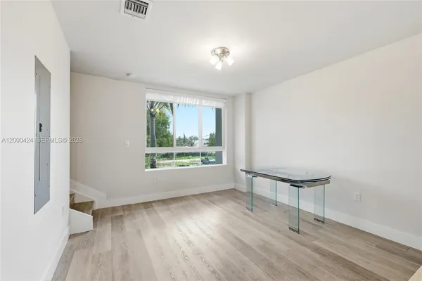 a view of an empty room with wooden floor and a window