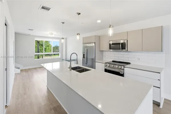 a kitchen with stainless steel appliances a stove a sink a microwave a refrigerator and cabinets