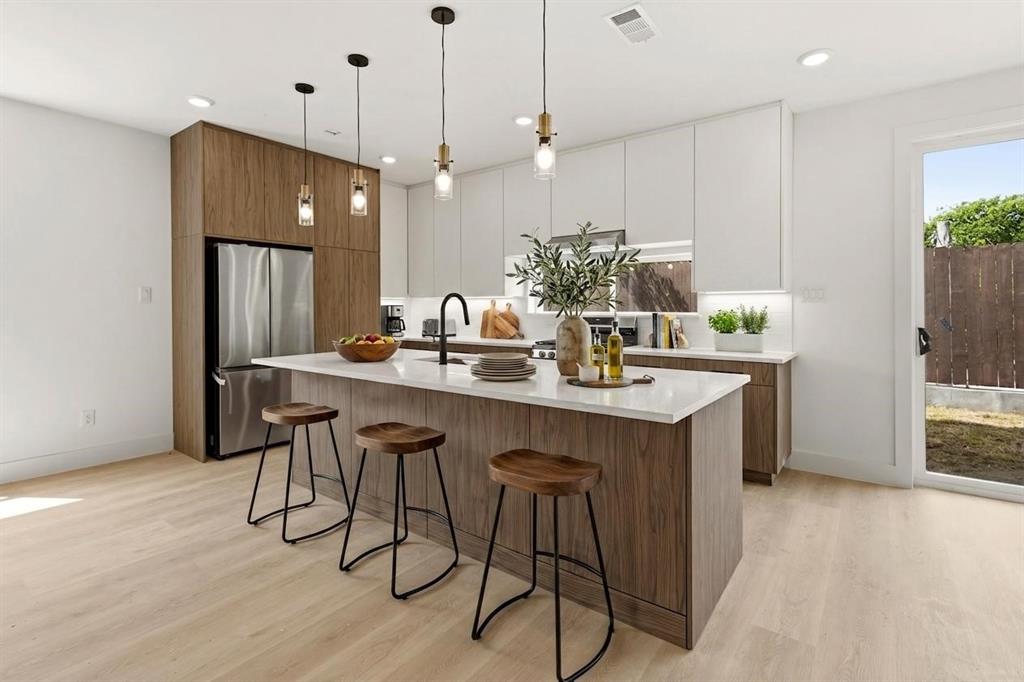 415 North Patton Avenue Dallas, TX 75203 - Photo 1 of 20 Modern kitchen featuring a large island with seating, a stainless steel refrigerator, and recessed lighting