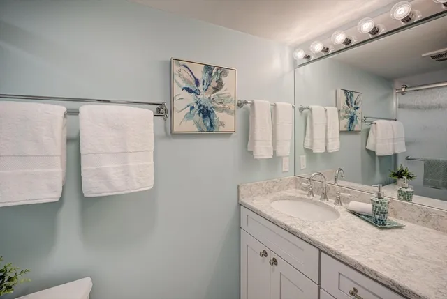a bathroom with a granite countertop sink a mirror and a shower
