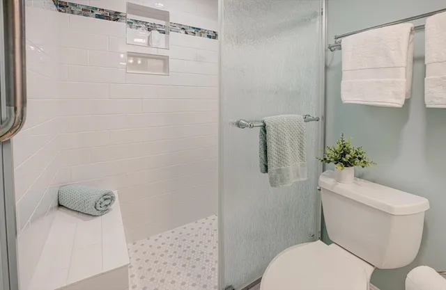 a white toilet sitting next to a shower