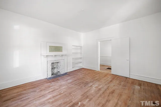 a view of empty room with a fireplace and wooden floor