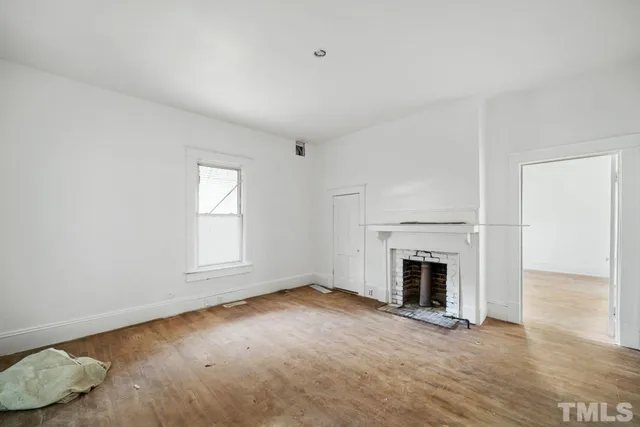 an empty room with fireplace cabinet and windows