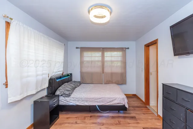 a bedroom with a bed and a flat tv screen on dresser