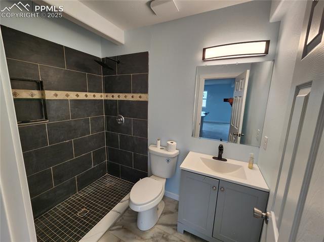 32174 Torrence Road Yoder, CO 80864 - Photo 8 of 13 Full bath with vanity, toilet, marble finish floor, and tiled shower