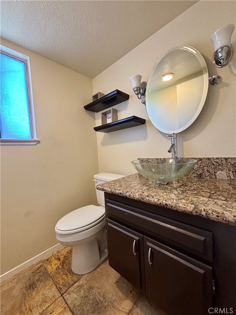 5715 Favela Drive Riverside, CA 92509 - Photo 4 of 27 a bathroom with a granite countertop toilet sink and mirror