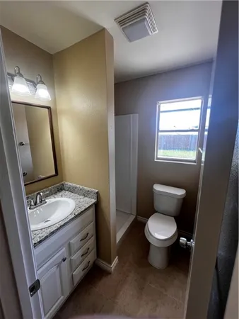a bathroom with a granite countertop toilet sink and mirror