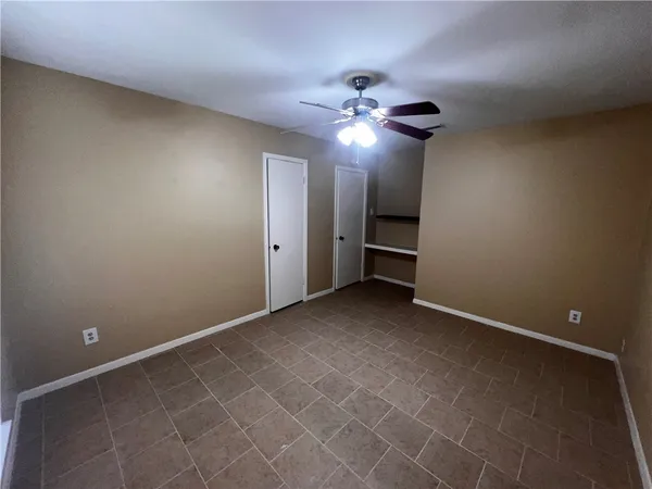 an empty room with a fan and a chandelier fan