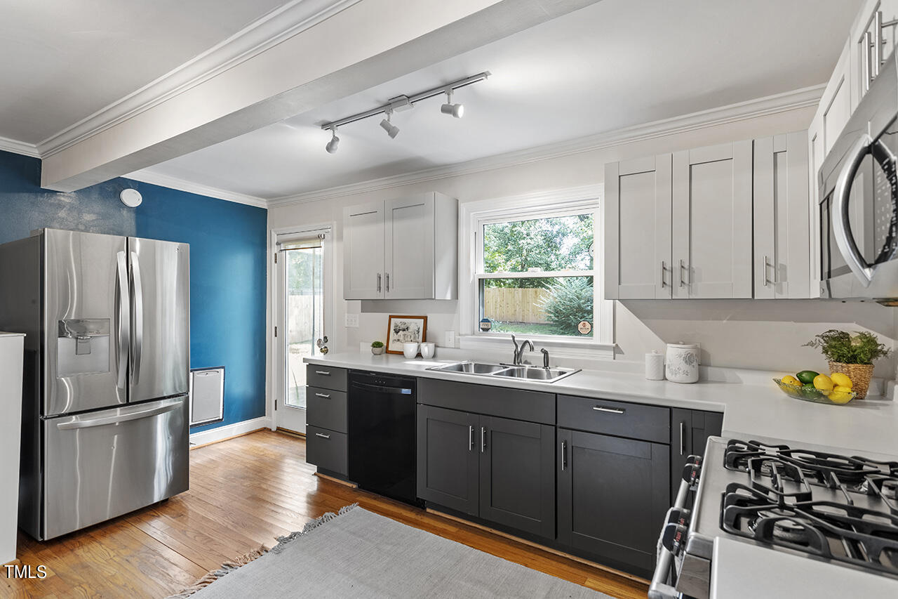1716 Bennett Street Raleigh, NC 27604 - Photo 9 of 30 a kitchen with stainless steel appliances a sink a stove a refrigerator cabinets and a window