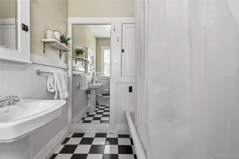 a bathroom with a black white checkered floor and a sink