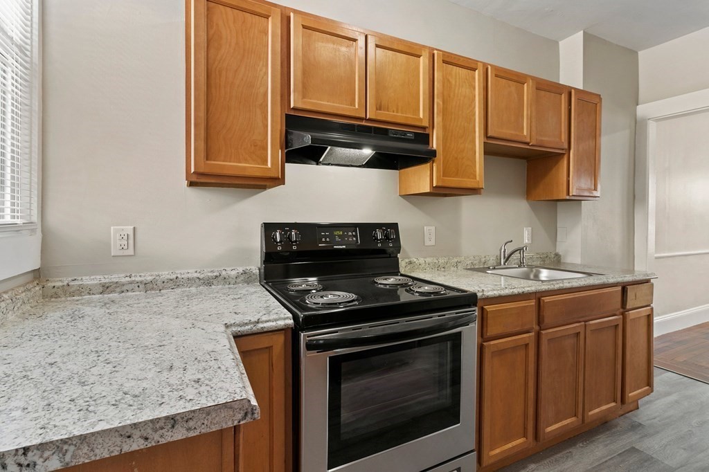 383 White Street Springfield, MA 01108 - Photo 18 of 39 a kitchen with granite countertop wood cabinets and a stove top oven