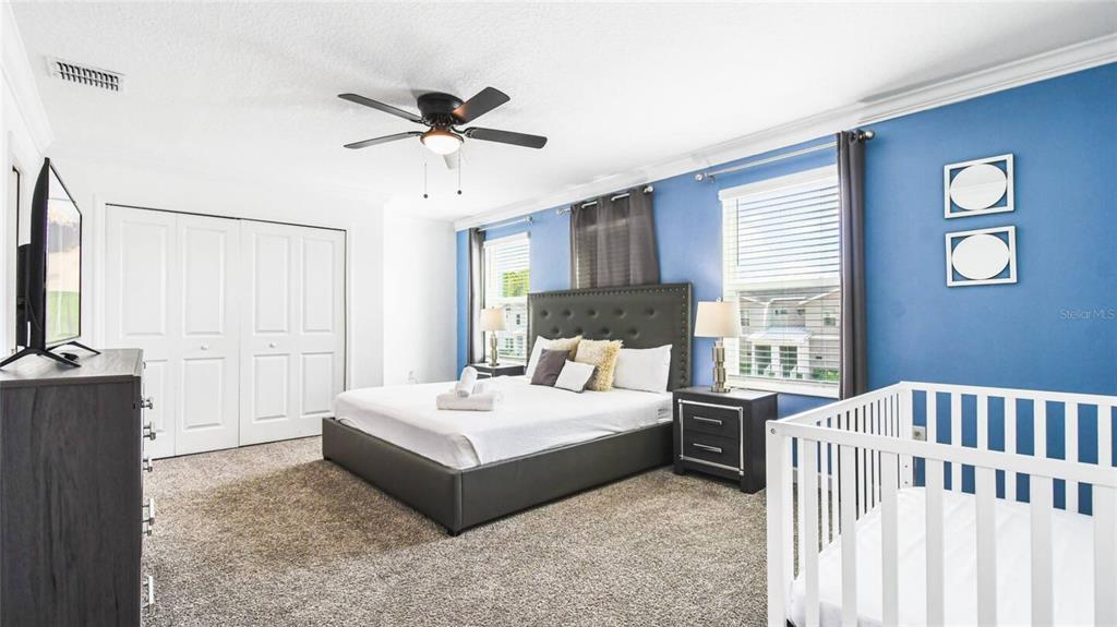 2916 Simile Street Kissimmee, FL 34746 - Photo 19 of 55 a spacious bedroom with a bed and a chandelier