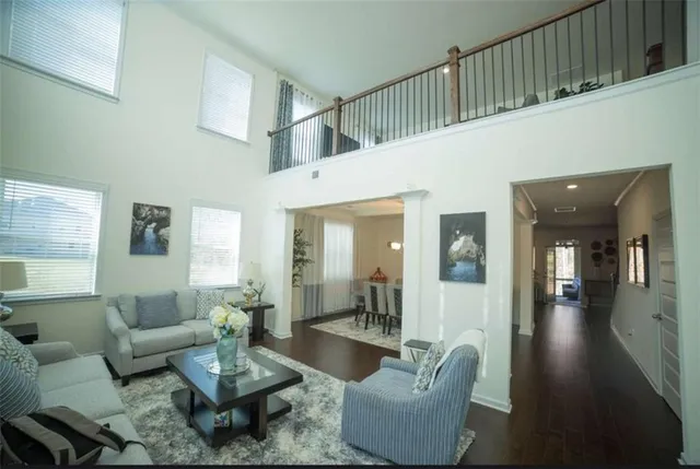 a living room with couches and a potted plant on table with wooden floor