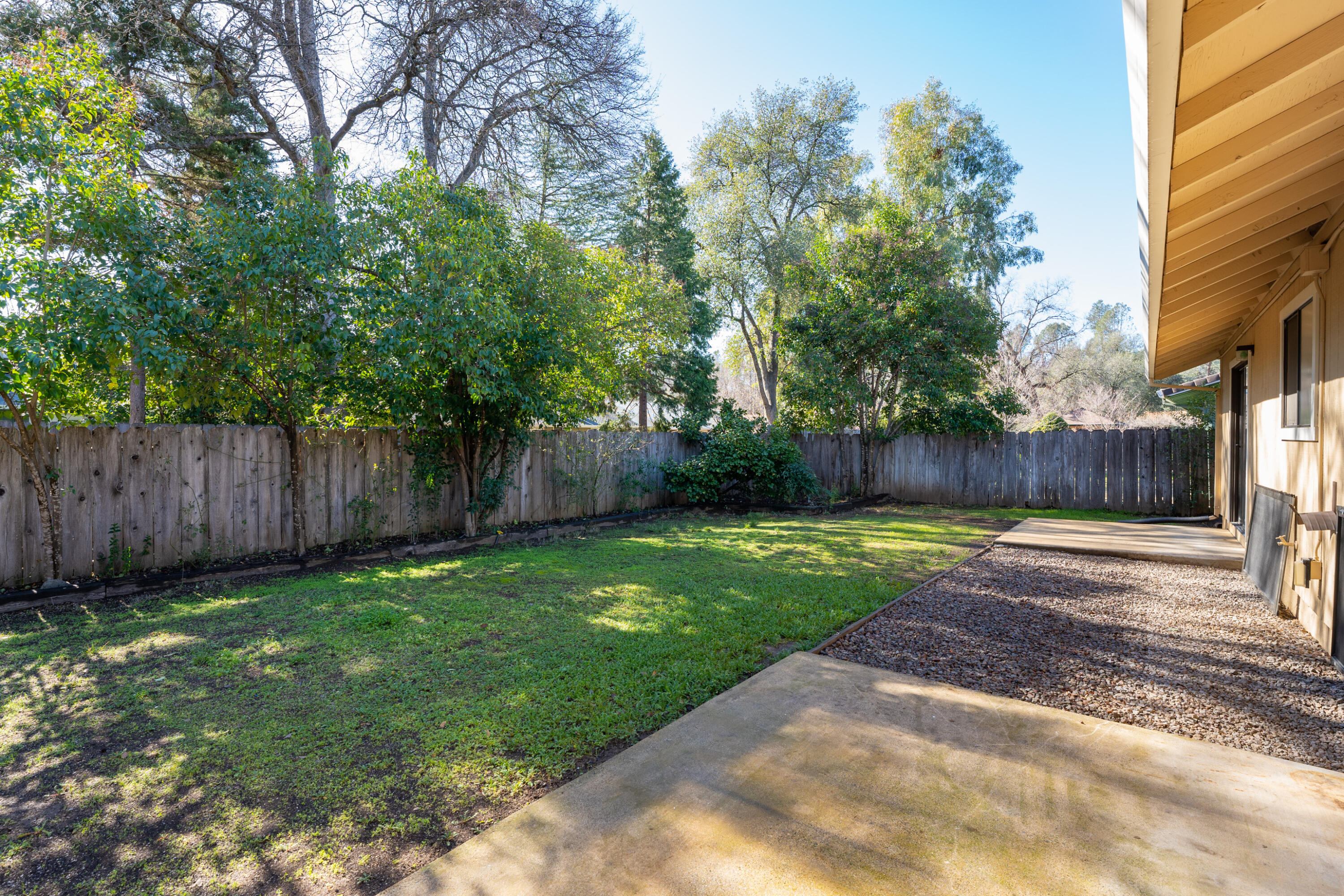 853 Oakmont Drive Redding, CA 96003 - Photo 24 of 37 a view of a backyard with large trees and wooden fence