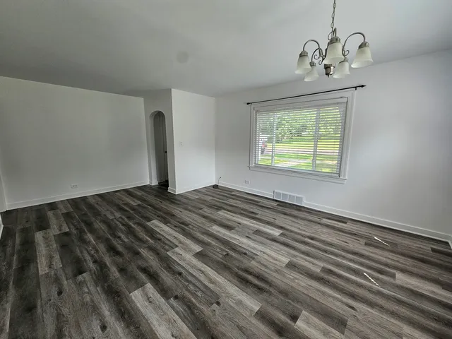 a view of empty room with window and wooden floor