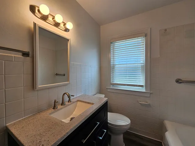 a bathroom with a granite countertop sink toilet and mirror