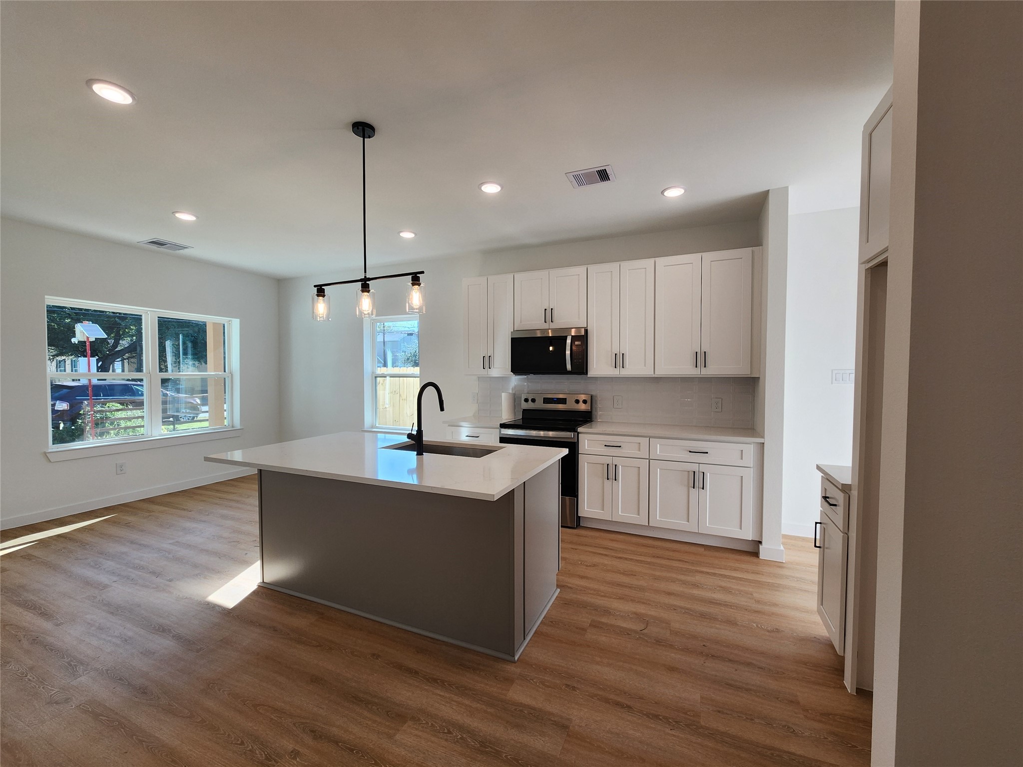 7817 Beckley Street, Unit A Houston, TX 77088 - Photo 4 of 18 a kitchen with kitchen island granite countertop wooden floors and white cabinets