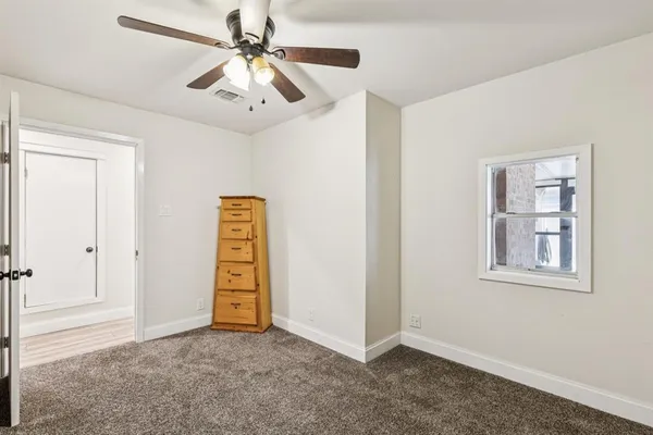 a view of an empty room with chandelier fan