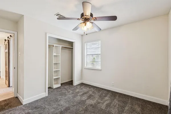 an empty room with a chandelier fan and windows