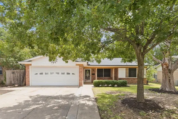 a view of a house with a yard and a large tree