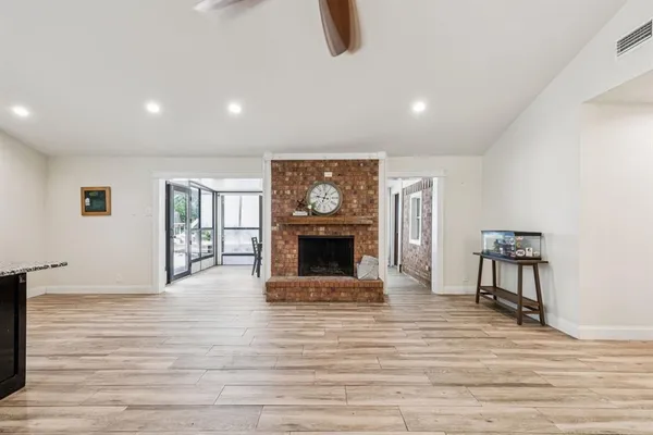 a view of an empty room with wooden floor fireplace and a window