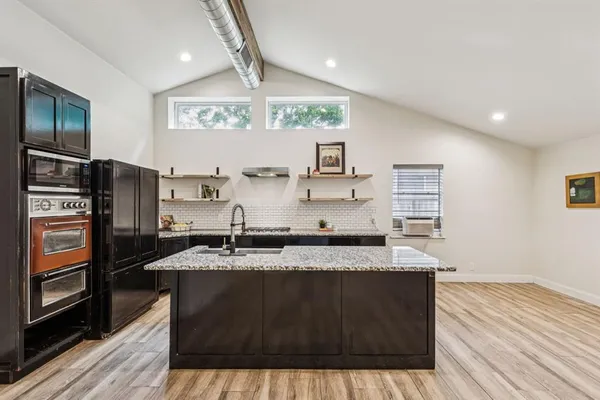 a kitchen with stainless steel appliances granite countertop a sink stove and wooden floor