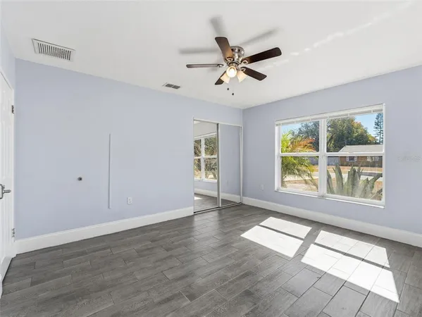 a view of an empty room with a window and wooden floor