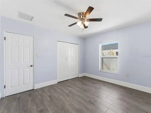 an empty room with wooden floor window and ceiling fan