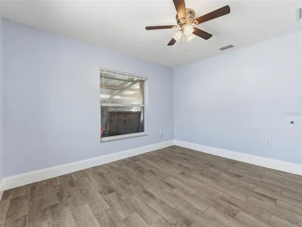 a view of an empty room with window and chandelier fan