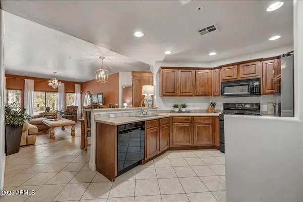 a kitchen with stainless steel appliances granite countertop a stove top oven a sink dishwasher a dining table and chairs with wooden floor