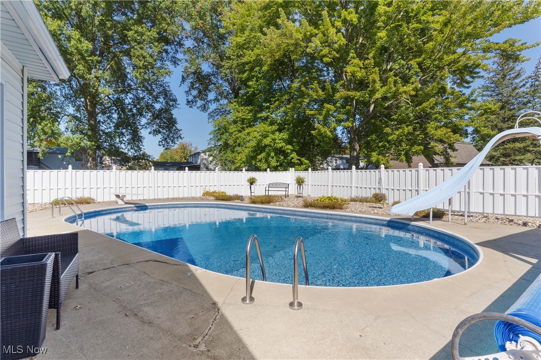 1757 East County Line Road Mineral Ridge, OH 44440 - Photo 32 of 40 View of swimming pool featuring a fenced backyard, a patio, a water slide, and a diving board