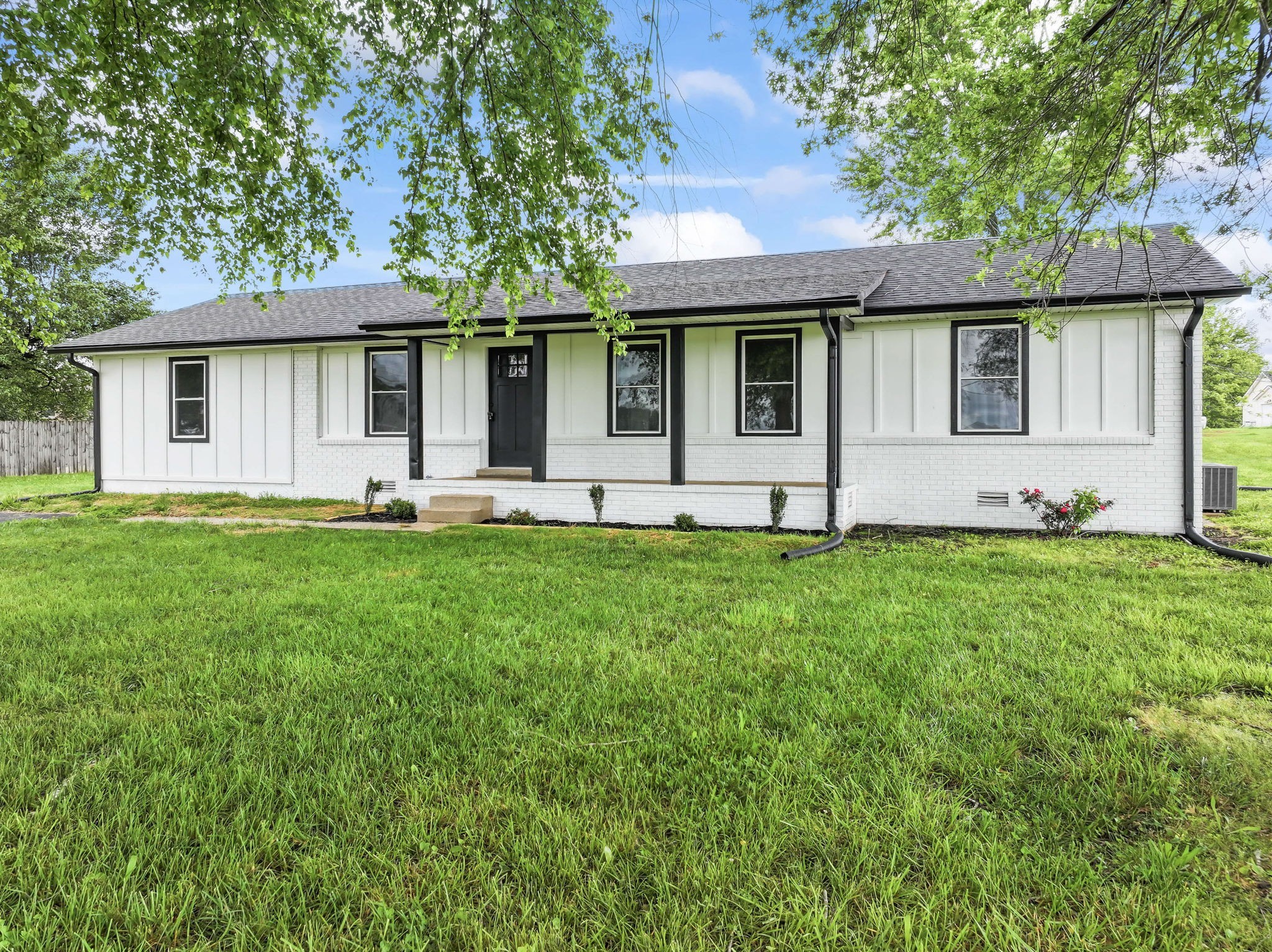 a front view of a house with a yard and a large tree