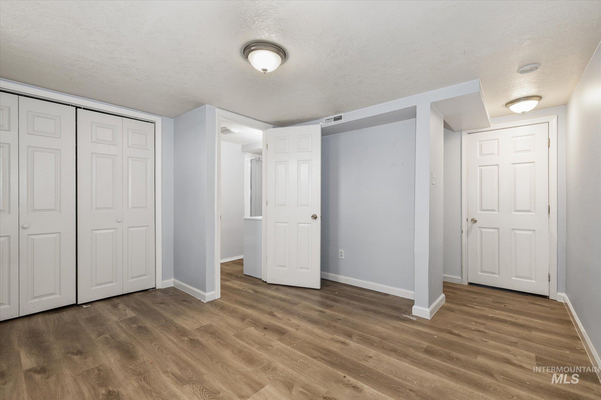 918 West 3rd Street Weiser, ID 83672 - Photo 28 of 36 Spacious room featuring wood-finish flooring, light grey walls, and multiple white bi-fold closet doors