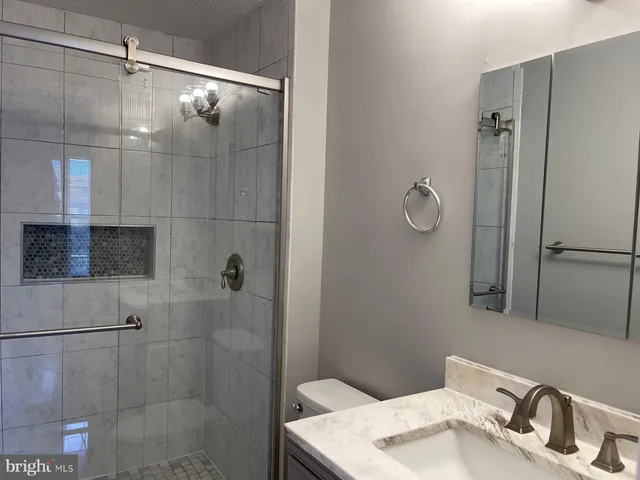 a bathroom with a granite countertop sink toilet and shower