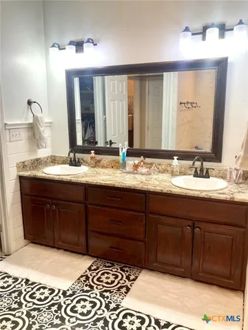 a bathroom with a granite countertop double vanity sink and a mirror