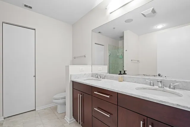 a bathroom with a granite countertop sink toilet and mirror