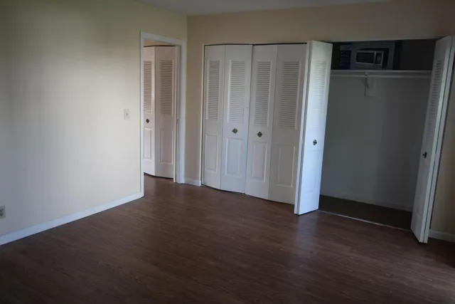 an empty room with wooden floor and closet area