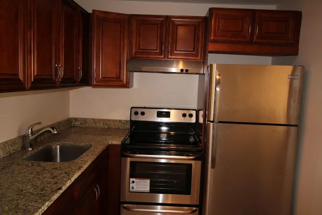 a kitchen with granite countertop a refrigerator stove and cabinets