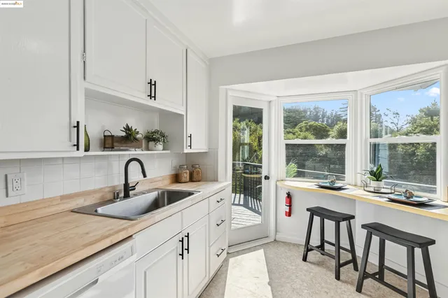a kitchen with stainless steel appliances a sink a stove and white cabinets next to a window