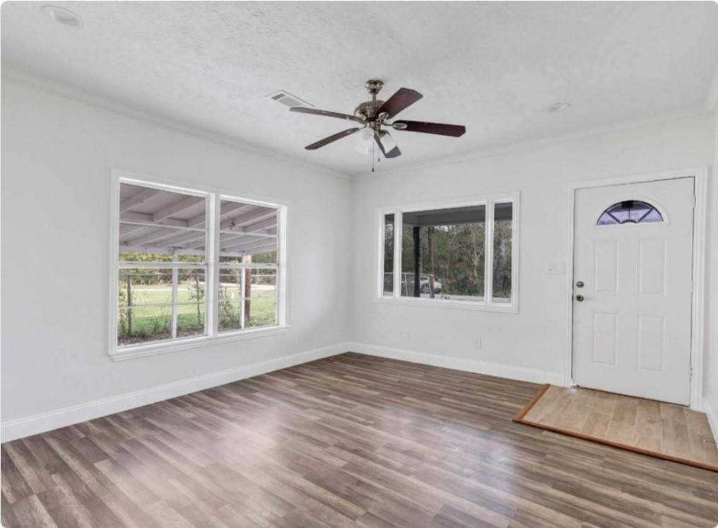 116 Trahan Street Ames, TX 77575 - Photo 5 of 23 a view of an empty room with a window and wooden floor