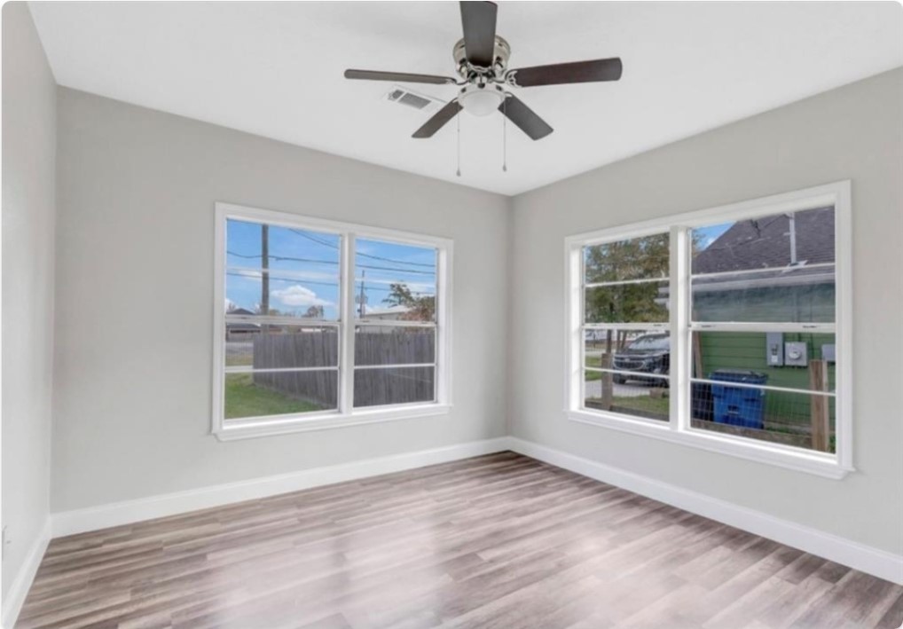 116 Trahan Street Ames, TX 77575 - Photo 7 of 23 a view of an empty room with a window and wooden floor