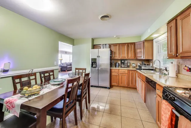 a kitchen with stainless steel appliances kitchen island granite countertop a table chairs and a refrigerator