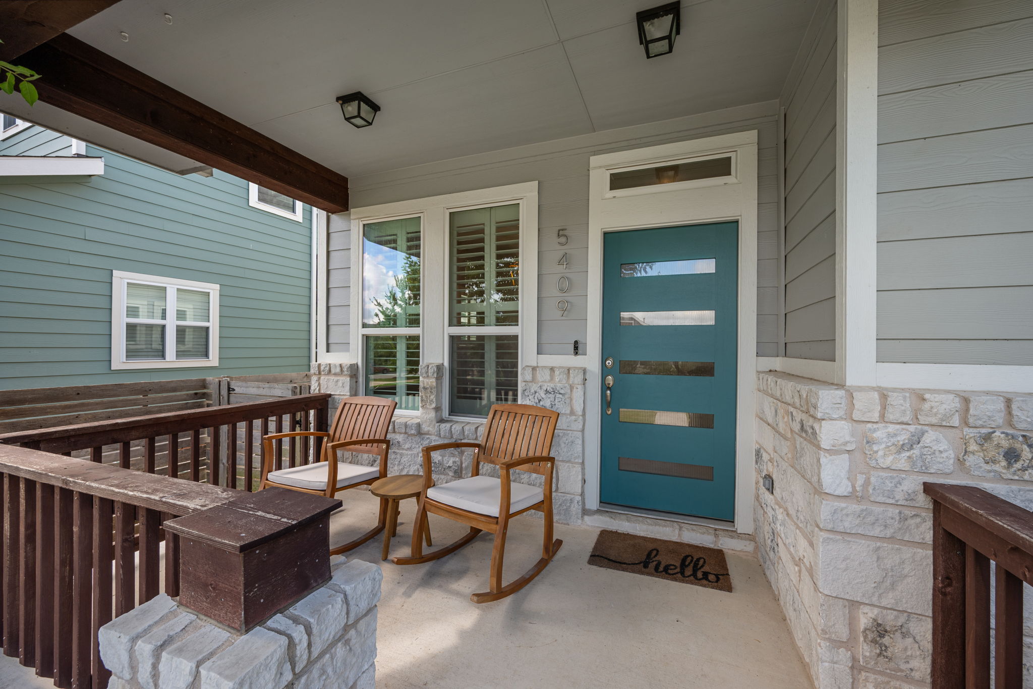 5409 Fox Wing Way Austin, TX 78747 - Photo 2 of 26 A welcoming front porch features a stylish teal entry door, creating a charming first impression.