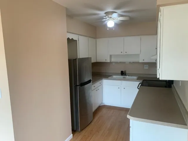 an empty room with wooden floor cabinet and windows